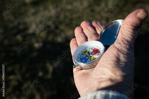 Fotografia Hand holding a travel compass, navigating in the outdoors, finding direction and