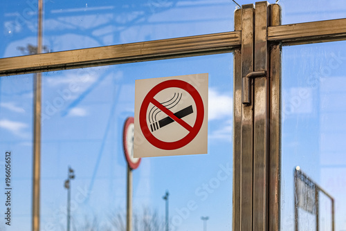 No Smoking Sign on Glass Barrier Against Clear Blue Sky