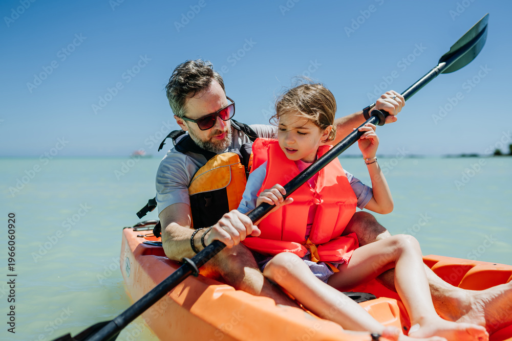Fototapeta premium Father kayaking with daughter on calm sea during family summer vacation.