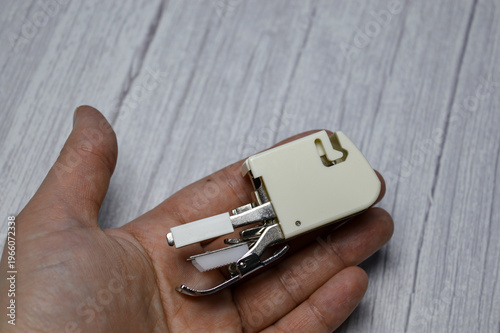 Fotografia hand holding sewing machine presser foot attachment