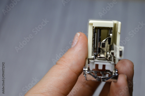Konstfotografi hand holding sewing machine presser foot attachment