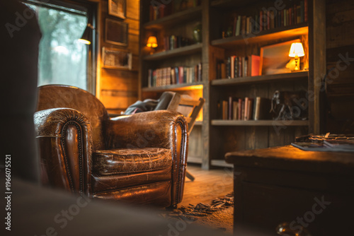 Slika na platnu Cozy leather armchair in a rustic library with warm ambient lighting