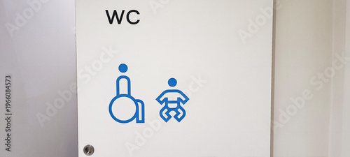 An accessible public restroom with wheelchair and baby changing symbols on the door and safety grab bars inside. Concepts of inclusivity, accessibility, and modern public infrastructure design.