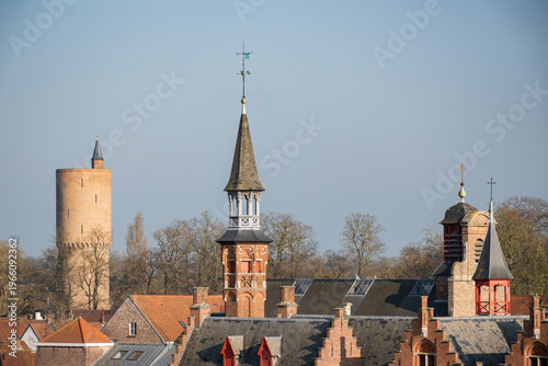 Bruges skyline with proinent architecture gunpowder tower Poertoren and Sint-Annakerk above rooftop cityscape. Belgium historic city European culture destination sunny day blue sky