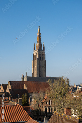 Bruges skyline with proinent gothic architecture tower church of our lady above rooftop cityscape. Belgium Onze Lieve Vrouwekerk popular tourist European culture destination sunny day blue sky