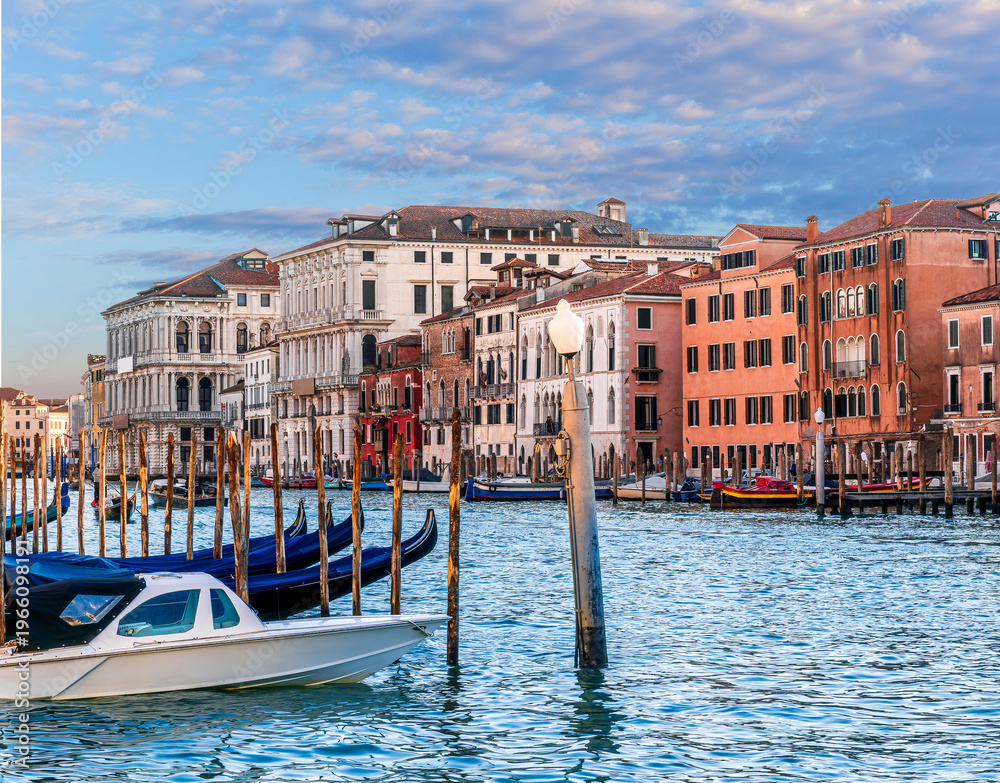 Fototapeta premium romantic view of a canal in Venice with boats and blue water and beautiful vintage buildings around the cityscape