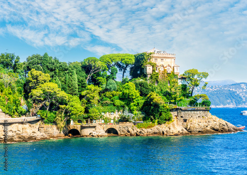 Beautiful italian coastline with green mountains and blue azure sea bay of Portofino gulf in Liguria. Panoramic landscape of luxury italian resort with boats in sea and cloudy sky.