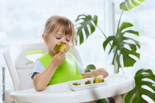 Cute little girl eating broccoli, vegetables for children as a source of vitamins, healthy lifestyle, vegetarian