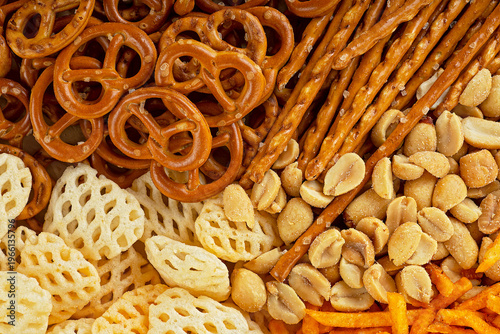Mix of salty snacks to go with beer: chips, pretzels, salted peanuts and crackers. Junk food backdrop.