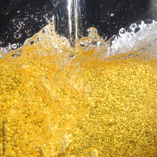 Beer. Jet of beer is poured into a beer glass, causing a lot of bubbles and foam. Beer background