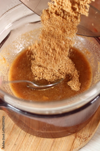 Pouring ground biscuits into melted butter. Making frozen strawberry cheesecake series.