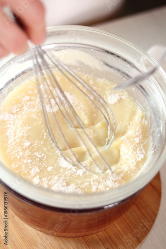 Adding and mixing powdered sugar and melted white chocolate. Making frozen strawberry cheesecake series.