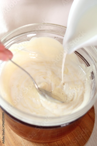 Pouring milk into melted white chocolate. Making frozen strawberry cheesecake series.
