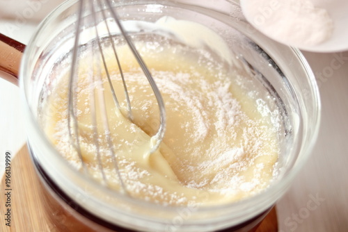 Adding and mixing powdered sugar and melted white chocolate. Making frozen strawberry cheesecake series.