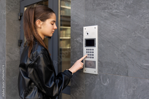 Tableau sur toile Young woman using intercom at apartment entrance