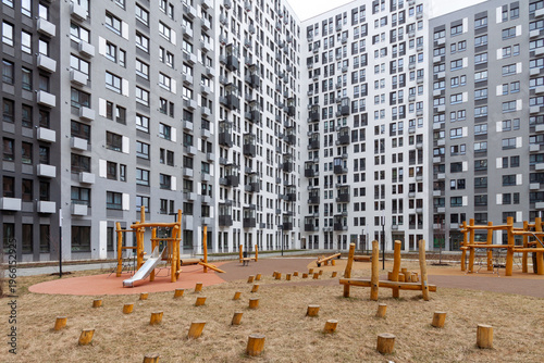 Modern residential courtyard with ecostyle natural wooden playground surrounded by high-rise apartment buildings