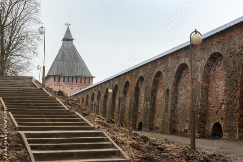 Ancient brick fortress wall with tower and stairway in historical cityscape