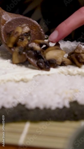 Homemade sushi spreading grilled mushrooms on sushi roll with rice and fresh cheese vertical