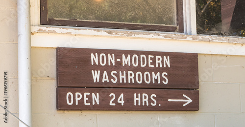 A non-modern washrooms open 24 hours wooden sign on a building in Winnipeg Beach, Manitoba, Canada 