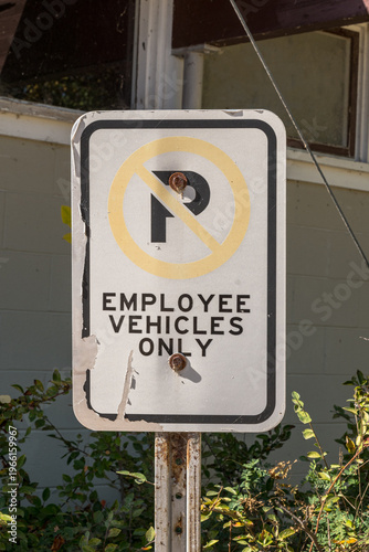 A faded employee vehicles only parking sign in front of a building in Winnipeg Beach, Manitoba, Canada on a sunny fall day