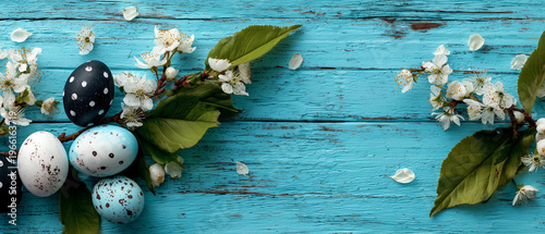 Speckled Easter eggs on blue wooden table with spring blossom branches rustic holiday background