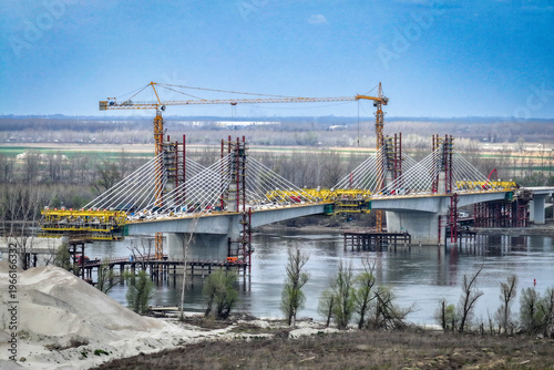 Large-scale construction of a modern cable-stayed bridge with tall tower cranes over a wide river