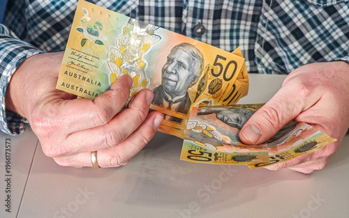 Male hands showing fan of Australian fifty dollar banknotes AUD currency for travel or payout