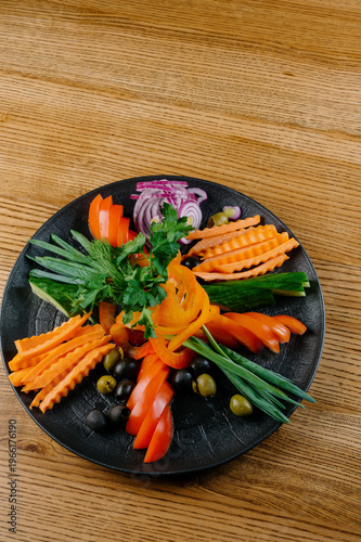 Foto Colorful vegetable platter with fresh herbs on a black plate