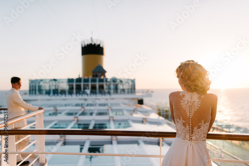 Bride and groom on cruise ship deck at sunset, ocean view in background