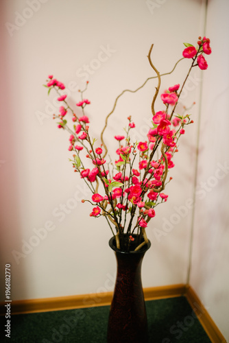 Decorative vase with pink cherry blossom branches in indoor setting
