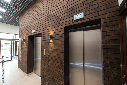 Modern elevator lobby with brick wall and stainless steel doors