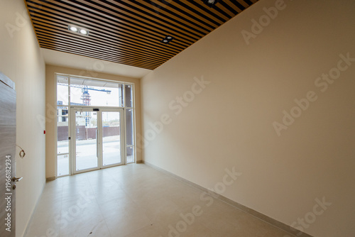 Empty commercial space interior with large windows and wooden ceiling
