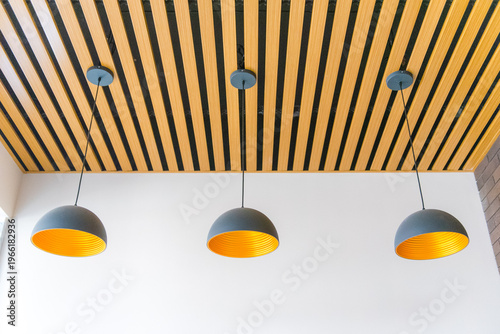 Modern pendant lights hanging from wooden slatted ceiling in contemporary space