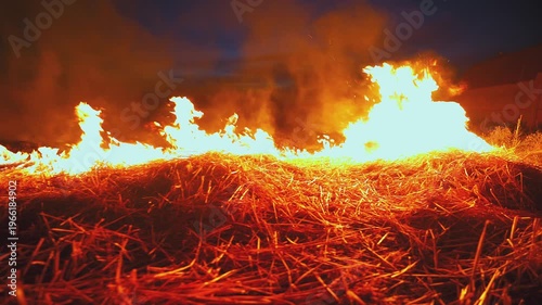 Kids stand near fast spreading flames in dry field. Intense heat and smoke. Uncontrolled rural fire. Environmental destruction and high risk situation.