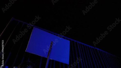 Night protest footage. Back view of moving sign. Light flashes like sirens. Urban streets, cinematic tension. Anonymous protester, text hidden. Dark, moody, dramatic motion scene.