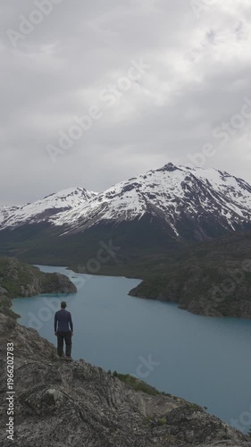 Man standing at a viewpoint overlooking Lake Belgrano and snow capped mountains in nature. Patagonia, Argentina