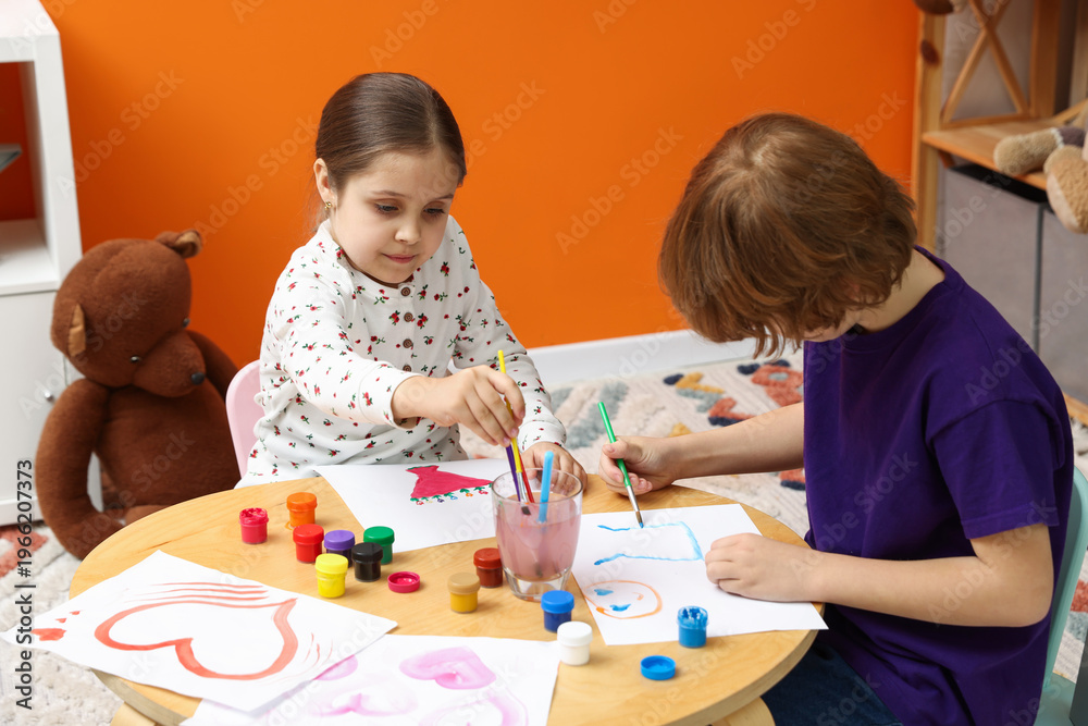 Obraz premium Cute little friends drawing together with brushes and paints at table indoors