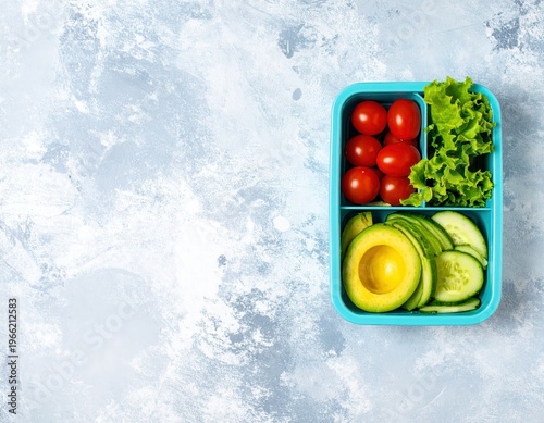 Contenitore ermetico blu con avocado, pomodorini, cetrioli e lattuga su sfondo grigio chiaro.