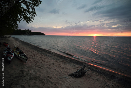 The sun sets over Lake Superior from a beach with kayaks in the Apostle Islands National Lakeshore in northern Wisconsin.