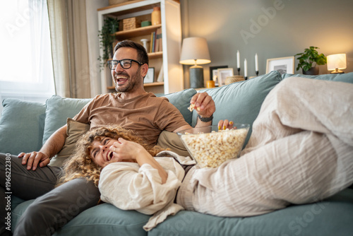Foto Happy young couple laughing watching movie at home