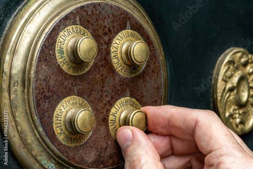 Tablou pe pânză Close-up of hand dialing combination lock on a vintage safe.