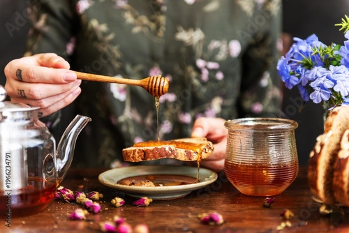 Tableau sur toile Honey drizzling on rustic bread.