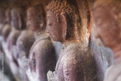 Row of ancient weathered Buddha statues in Wat Umong cave temple in Chiang Mai
