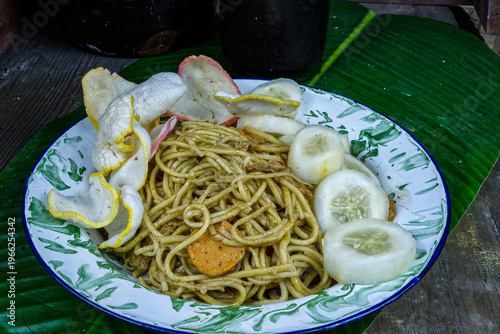 Wallpaper Mural A plate of mie goreng served on a banana leaf with sliced cucumbers and egg wedges in a casual outdoor setting in Indonesia. Torontodigital.ca