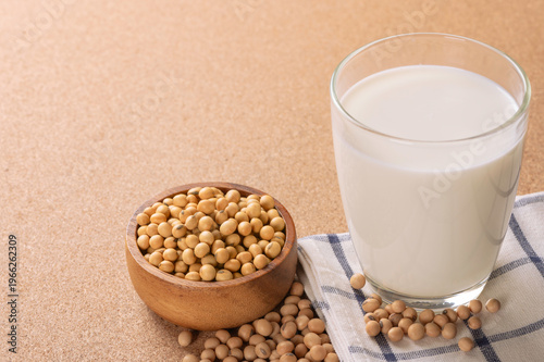 Obraz na plátne Glass of nutritious white soy milk served with organic soybeans in wooden bowl on brown background
