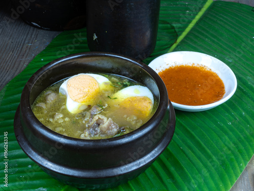 Wallpaper Mural Traditional Indonesian soto daging soup with telur served in a black bowl on a green banana leaf with a side of spicy sauce Torontodigital.ca