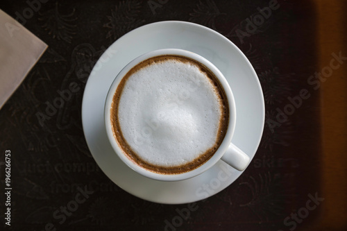 Hot Cappuccino Coffee Cup with Milk Foam Top View on Wooden Table . Top view