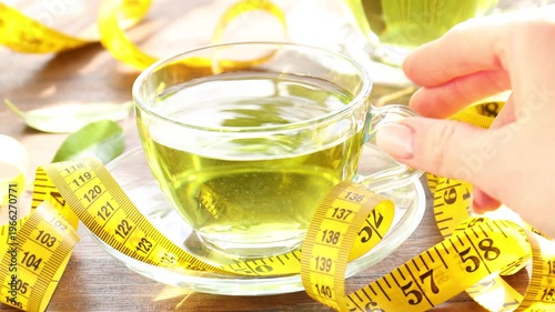Woman pouring weight loss tea into cup at wooden table, closeup