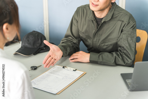 Fotografie A male mechanic and a female customer are explaining, quoting, and proposing solutions at the reception desk of an auto repair shop