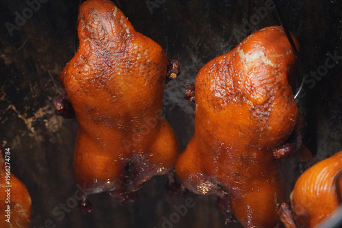 Wallpaper Mural Roasted ducks, also known as bebek, hang from hooks in a kitchen, showcasing their crispy, golden-brown skin with a dark background in Indonesia. Torontodigital.ca